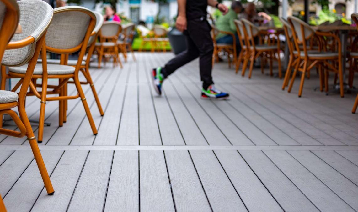Serveur en mouvement sur la terrasse d'un restaurant de couleur gris anthracite
